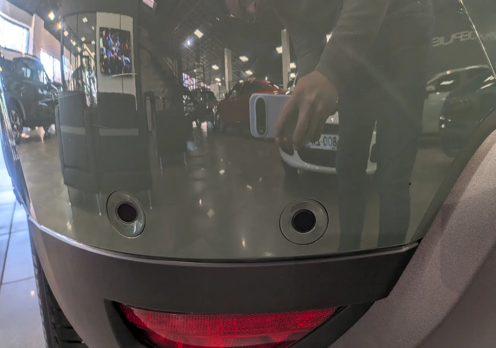 Gros plan sur le pare-chocs arrière kaki du Dacia Duster 2023, montrant les capteurs de recul et le feu rouge intégré.