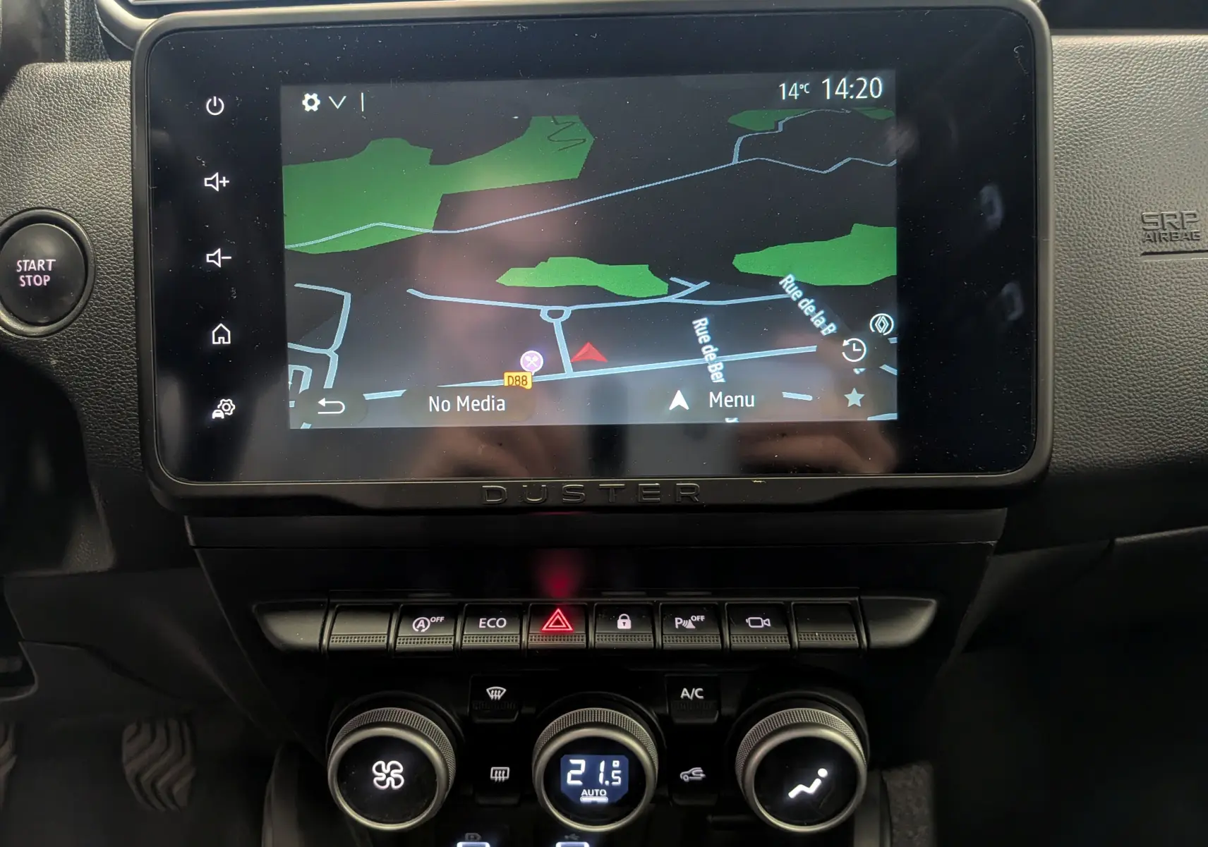 Vue rapprochée de l'écran tactile central du Dacia Duster 2023 affichant la navigation avec commandes climatisation en dessous.