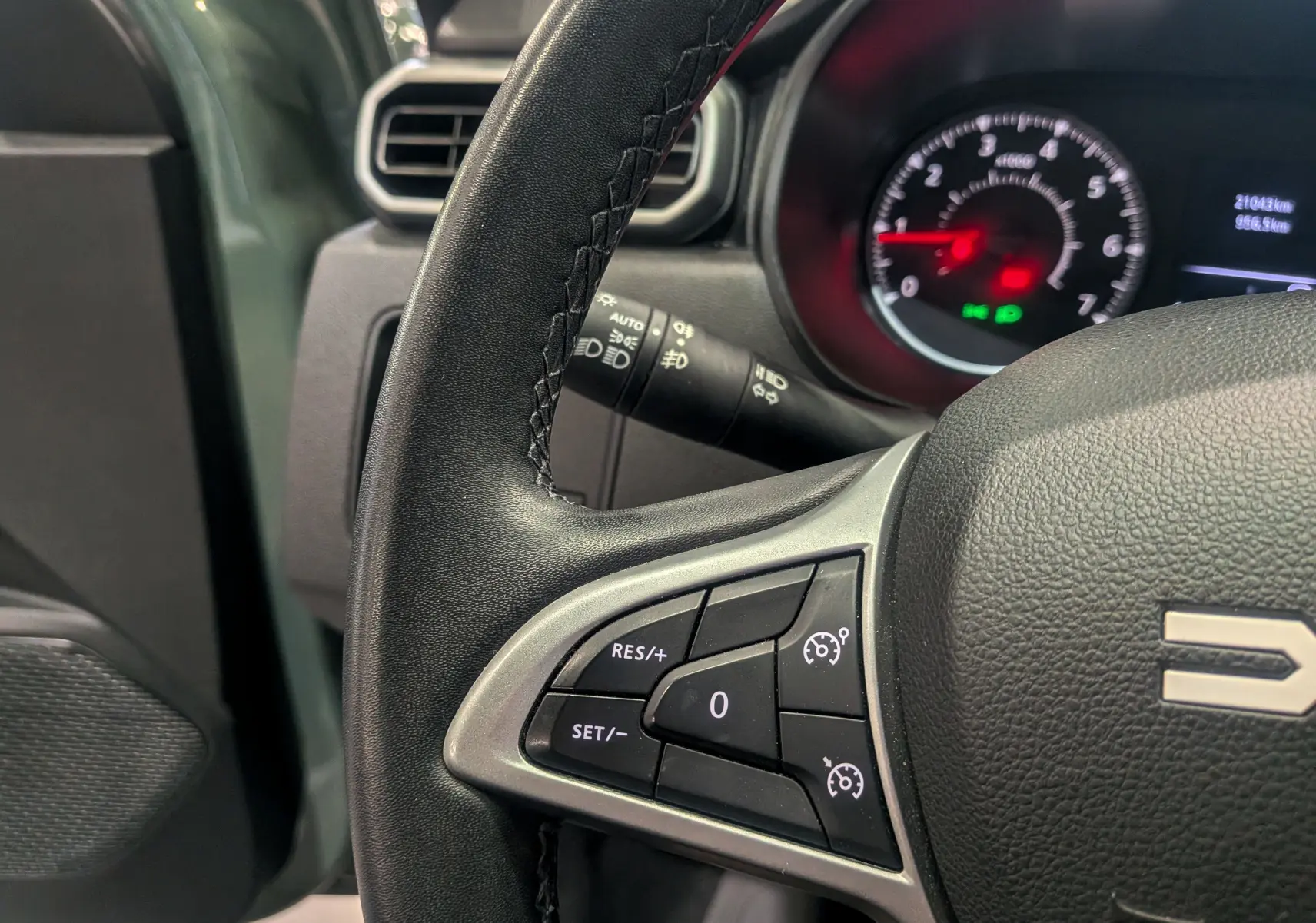 Gros plan sur le volant et le compteur du Dacia Duster 2023 kaki, montrant les commandes de régulateur de vitesse.