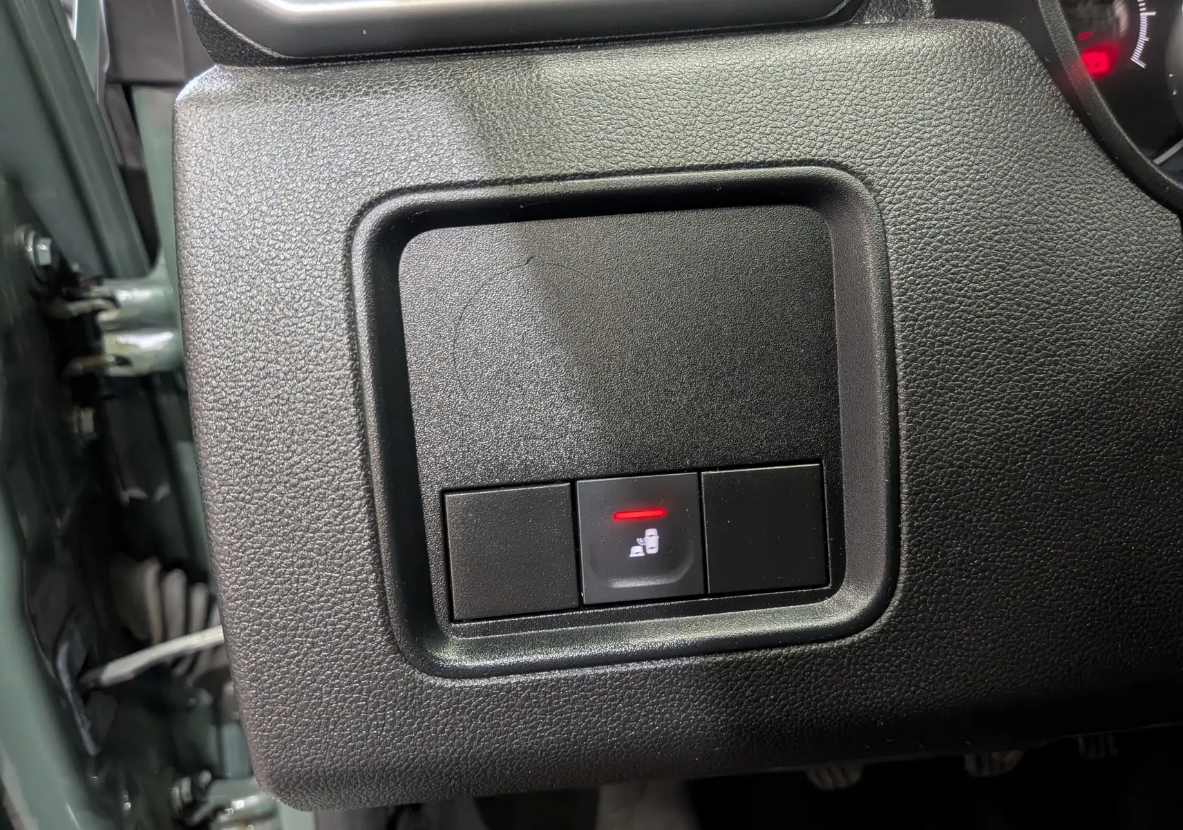 Gros plan sur le bouton de verrouillage centralisé du tableau de bord côté gauche du Dacia Duster kaki 2023.