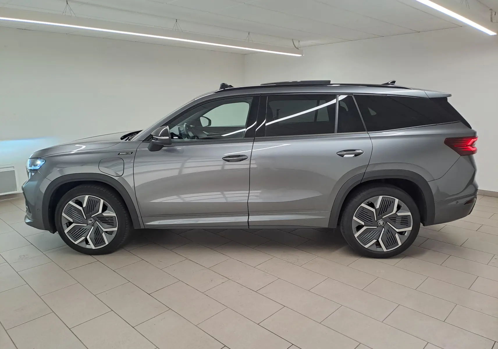 Vue de profil côté gauche du Skoda Kodiaq gris graphite avec jantes alliage 20 pouces et toit panoramique ouvrant.