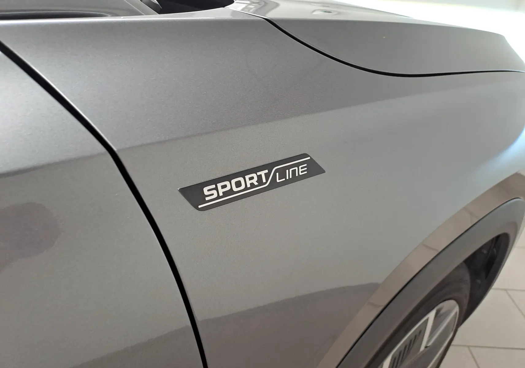 Gros plan sur l'aile avant droite gris graphite du Skoda Kodiaq 2025 avec badge Sportline visible.