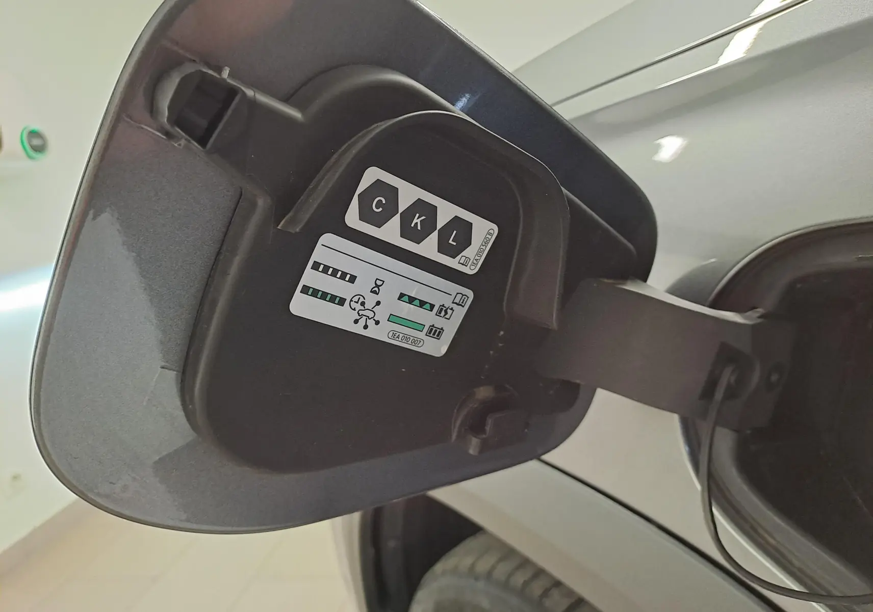 Gros plan sur la trappe de recharge côté gauche du Skoda Kodiaq gris graphite, version hybride rechargeable 2025.