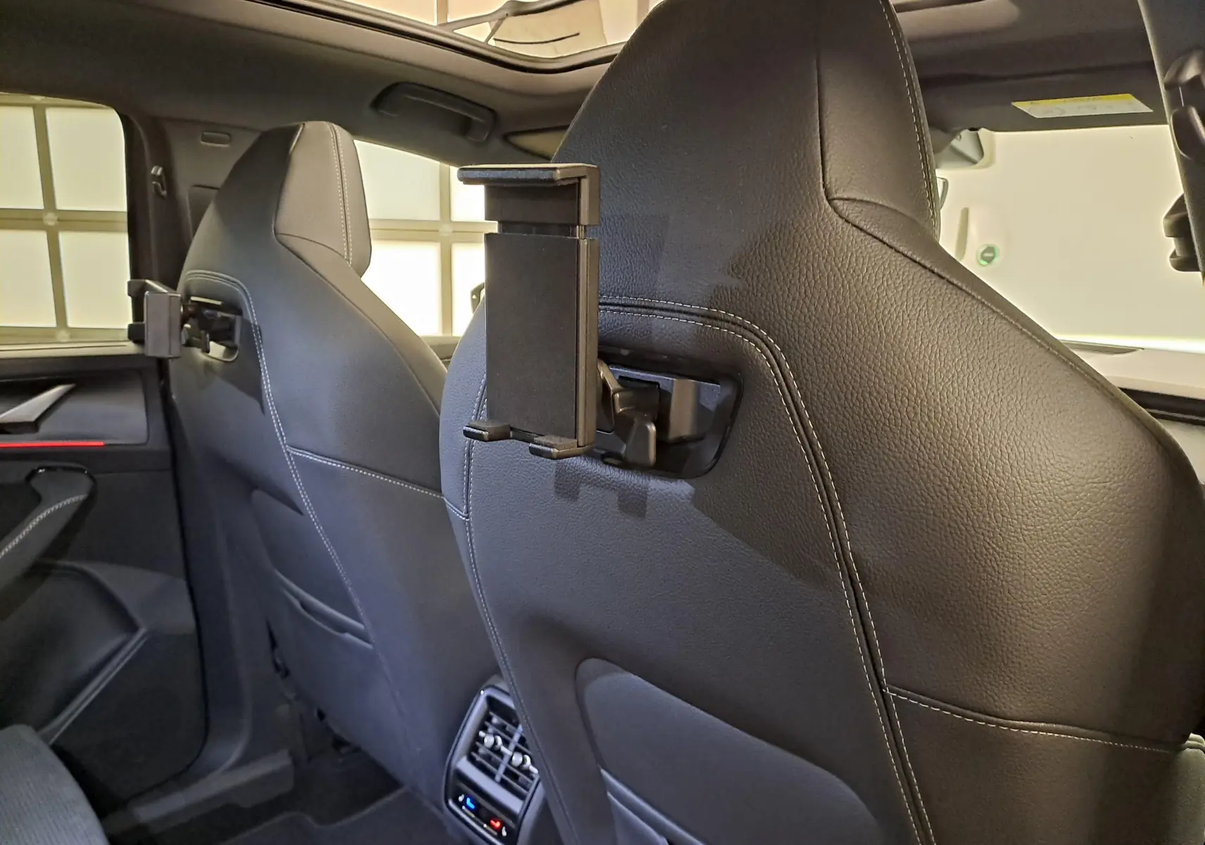 Vue intérieure arrière du Skoda Kodiaq 2025, sièges en cuir noir avec support tablette fixé au dossier côté droit.