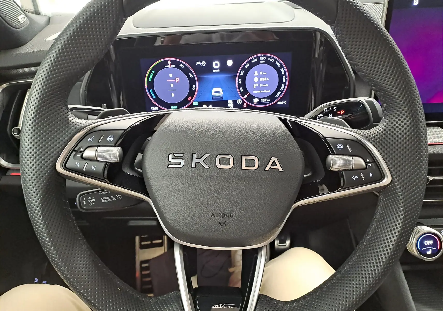 Vue rapprochée du volant perforé SKODA avec tableau de bord numérique et commandes intégrées, intérieur moderne et épuré.