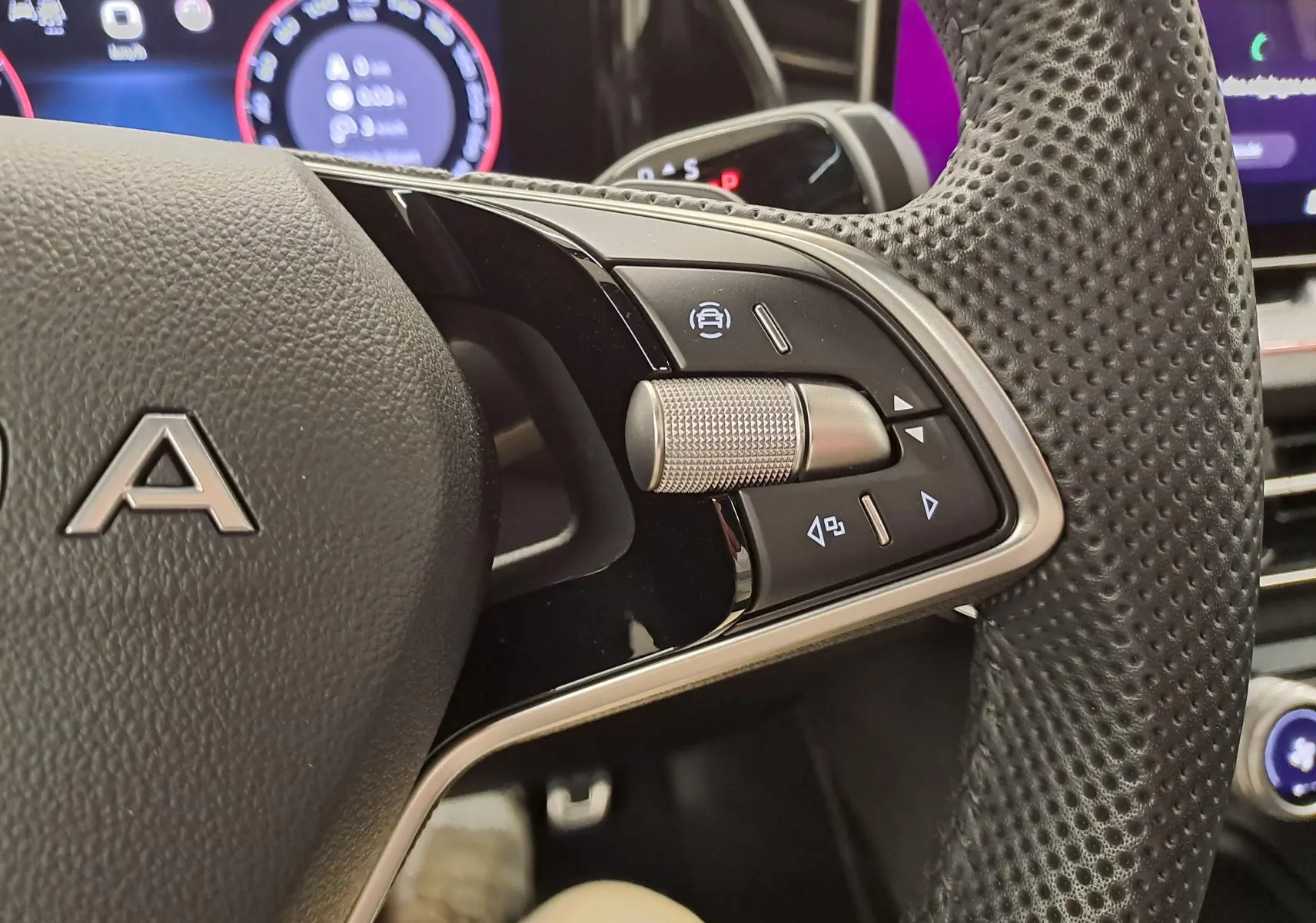 Gros plan sur les commandes à droite du volant perforé d'une Skoda Kodiaq 2025, tableau de bord numérique en arrière-plan.