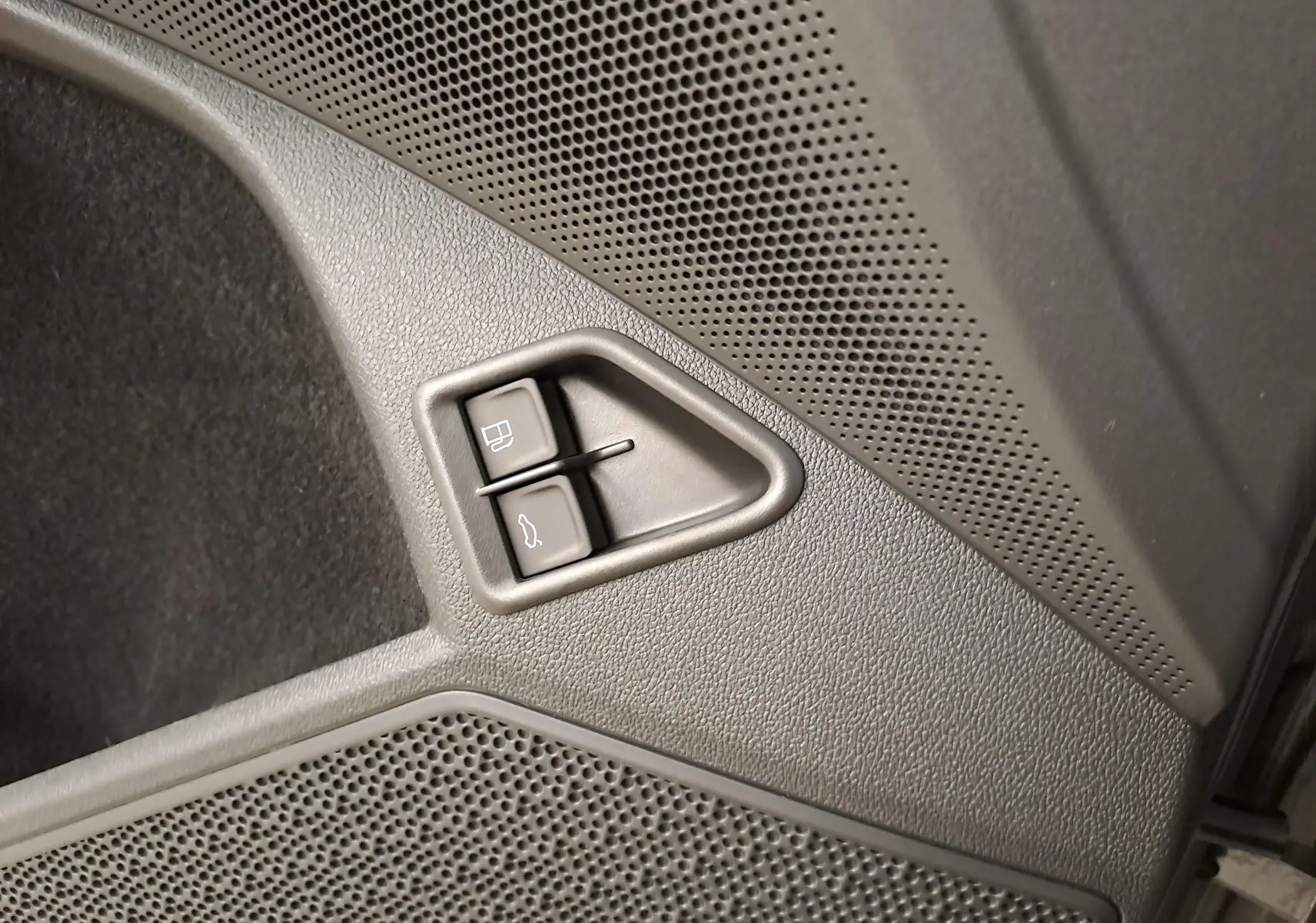 Gros plan sur les boutons d'ouverture de trappe à carburant et coffre dans l'habitacle gris du Skoda Kodiaq 2025.
