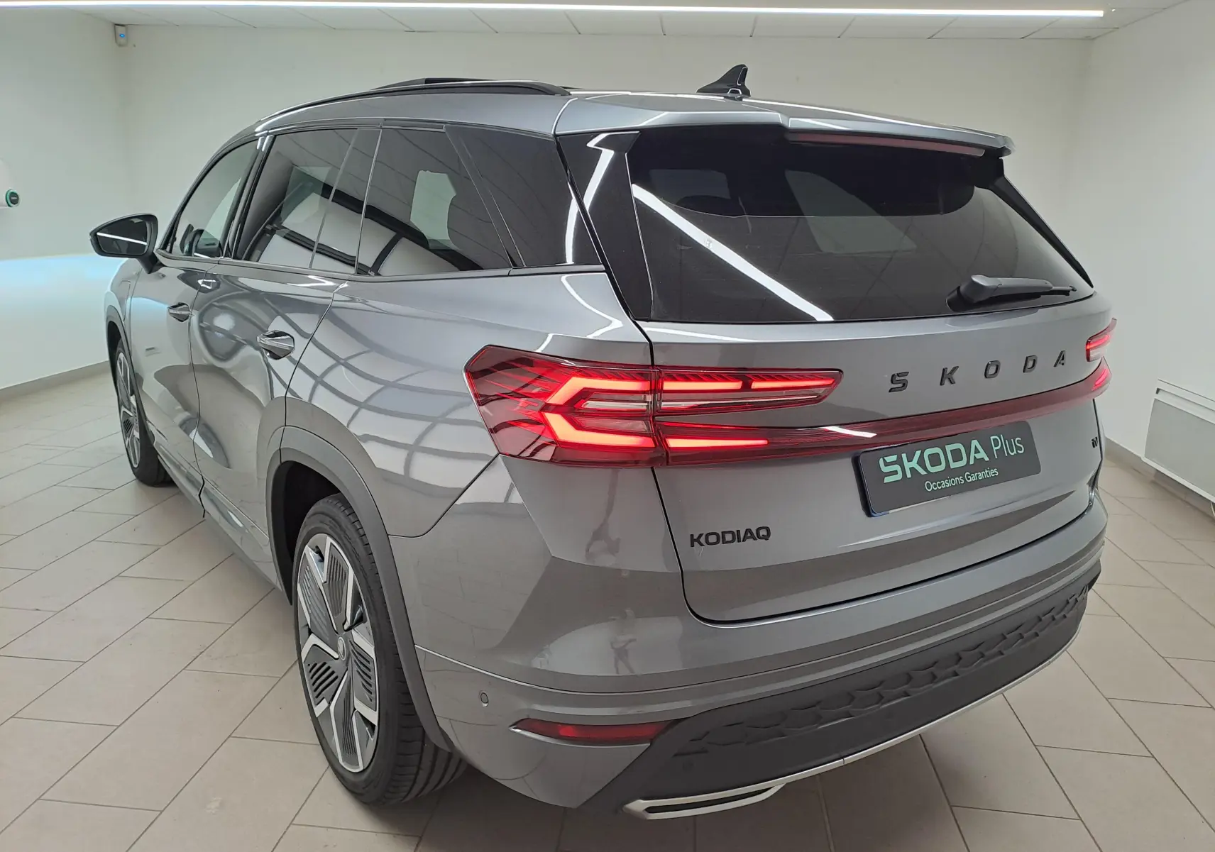 Vue 3/4 arrière droite du Skoda Kodiaq gris graphite avec feux arrière LED allumés et jantes alliage 20 pouces.