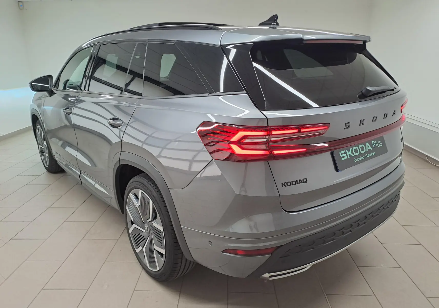 Vue 3/4 arrière droite du Skoda Kodiaq gris graphite avec feux arrière allumés et jantes alliage 20 pouces.