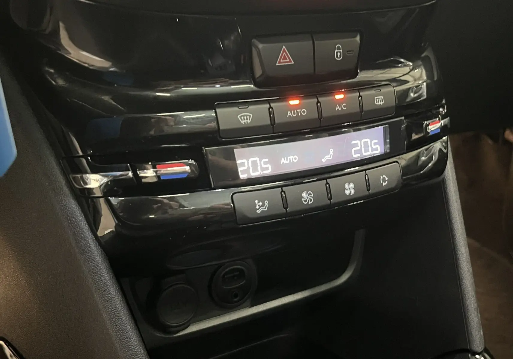 Gros plan sur la console centrale noire du Peugeot 2008, affichant la climatisation automatique réglée à 20,5°C.