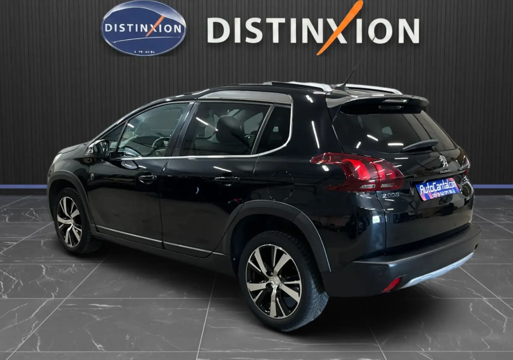 Peugeot 2008 noir vue 3/4 arrière droit, avec jantes alliage et barres de toit, stationnée en intérieur showroom.