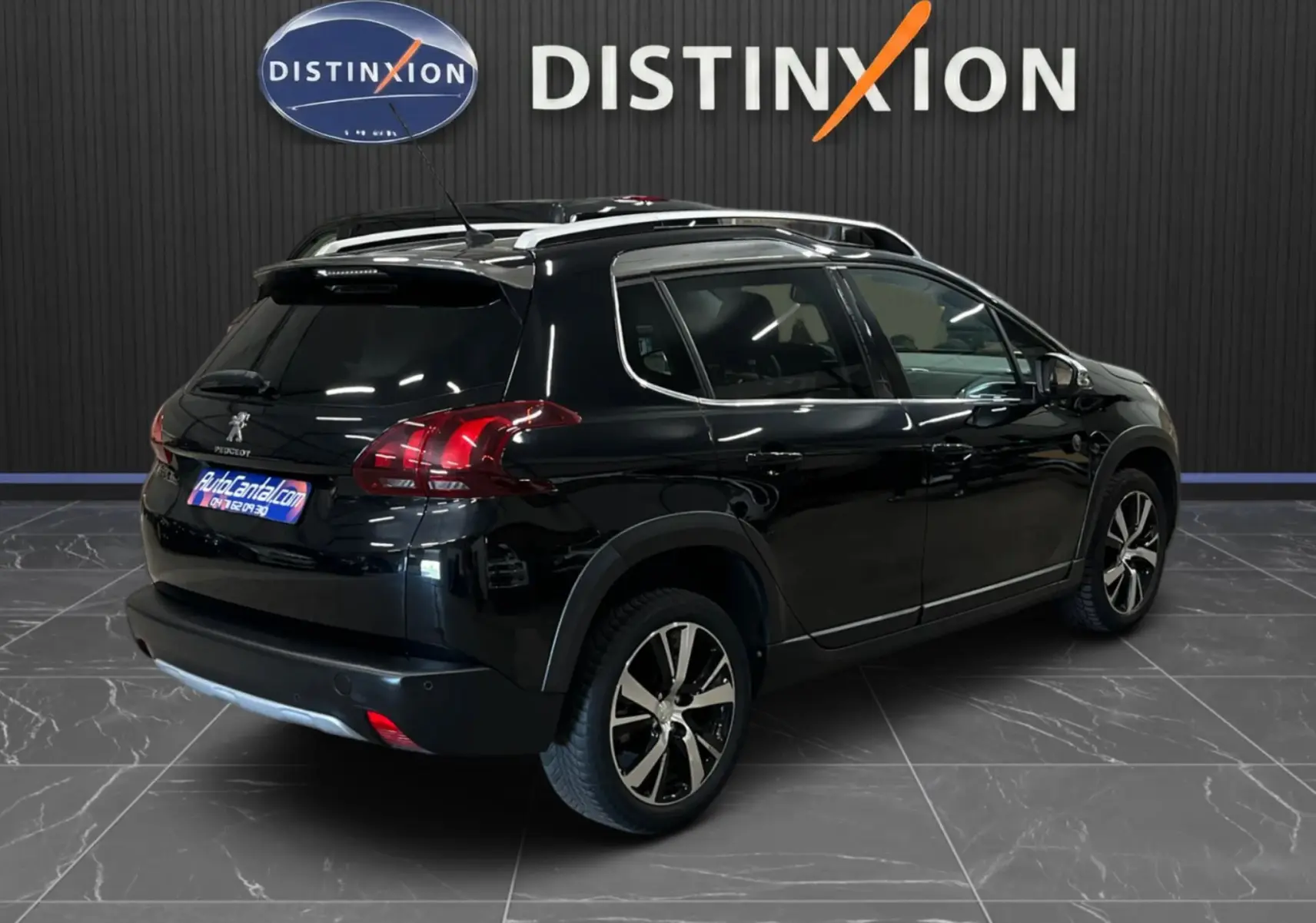 Vue 3/4 arrière droite d’un Peugeot 2008 noir avec jantes alliage et barres de toit, en intérieur showroom.