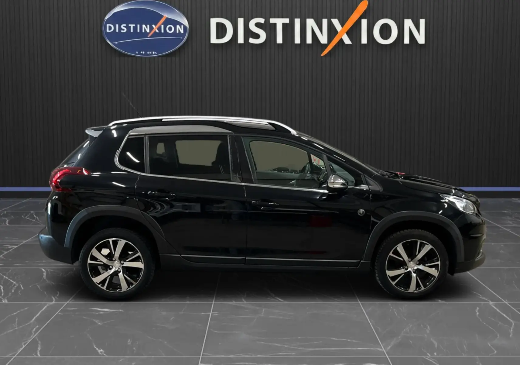 Profil droit d’un Peugeot 2008 Crossway noir de 2018 avec jantes alliage et barres de toit visibles en intérieur showroom.