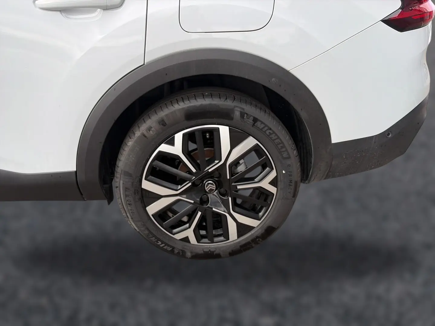 Gros plan sur la roue arrière droite de la Citroën C4 X blanche, avec jante alliage noire et argentée, et feu arrière partiel visible.