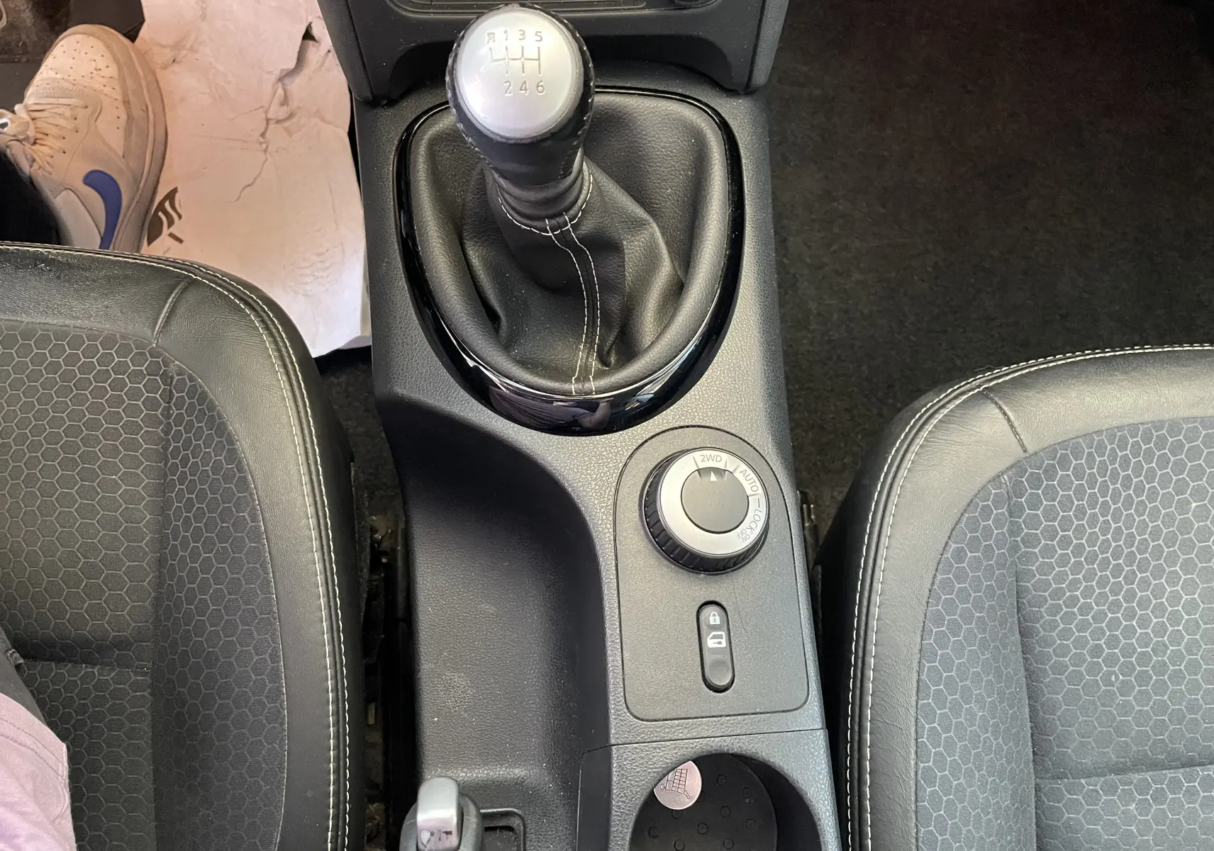 Vue plongeante sur la console centrale du Nissan Qashqai blanc, avec levier de vitesses manuel et sélecteur 4x4.