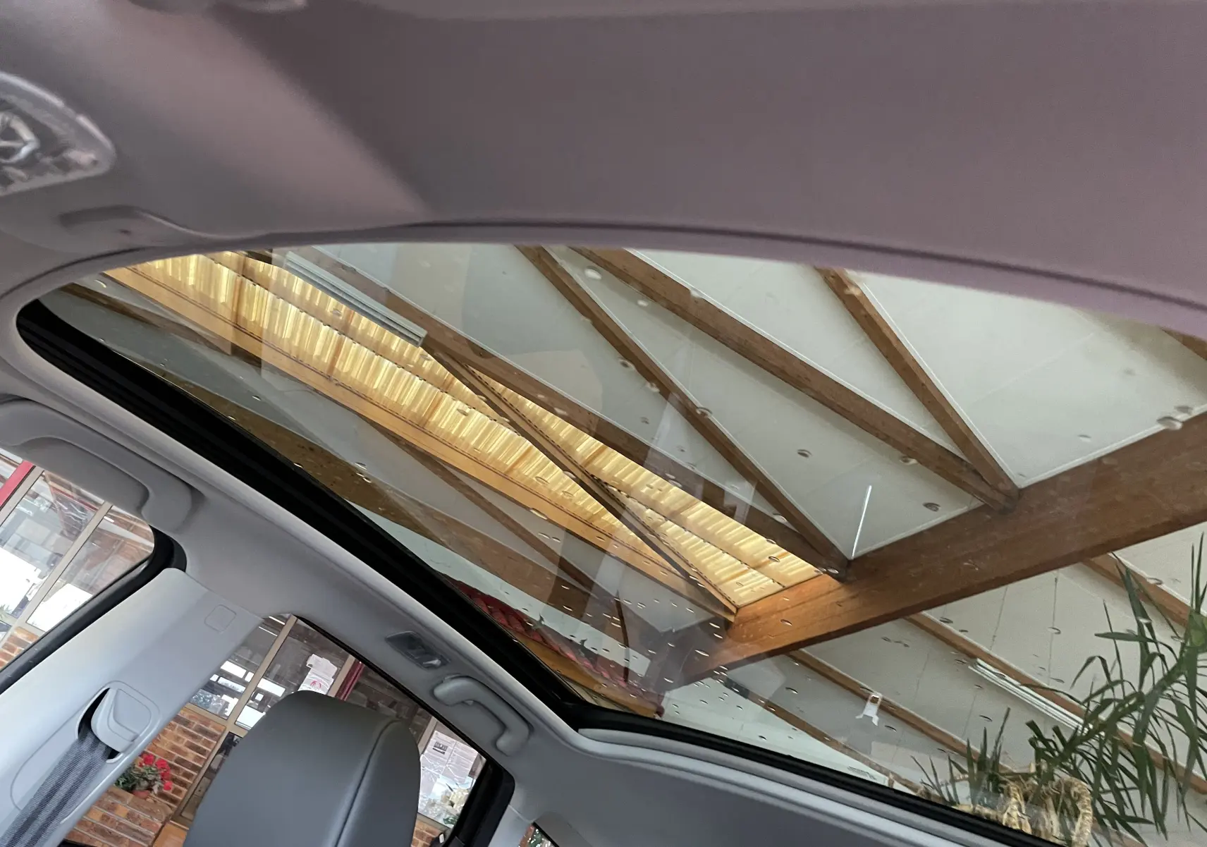 Toit panoramique ouvert vu de l'intérieur du Nissan Qashqai blanc, soulignant la luminosité et la structure en bois au-dessus.