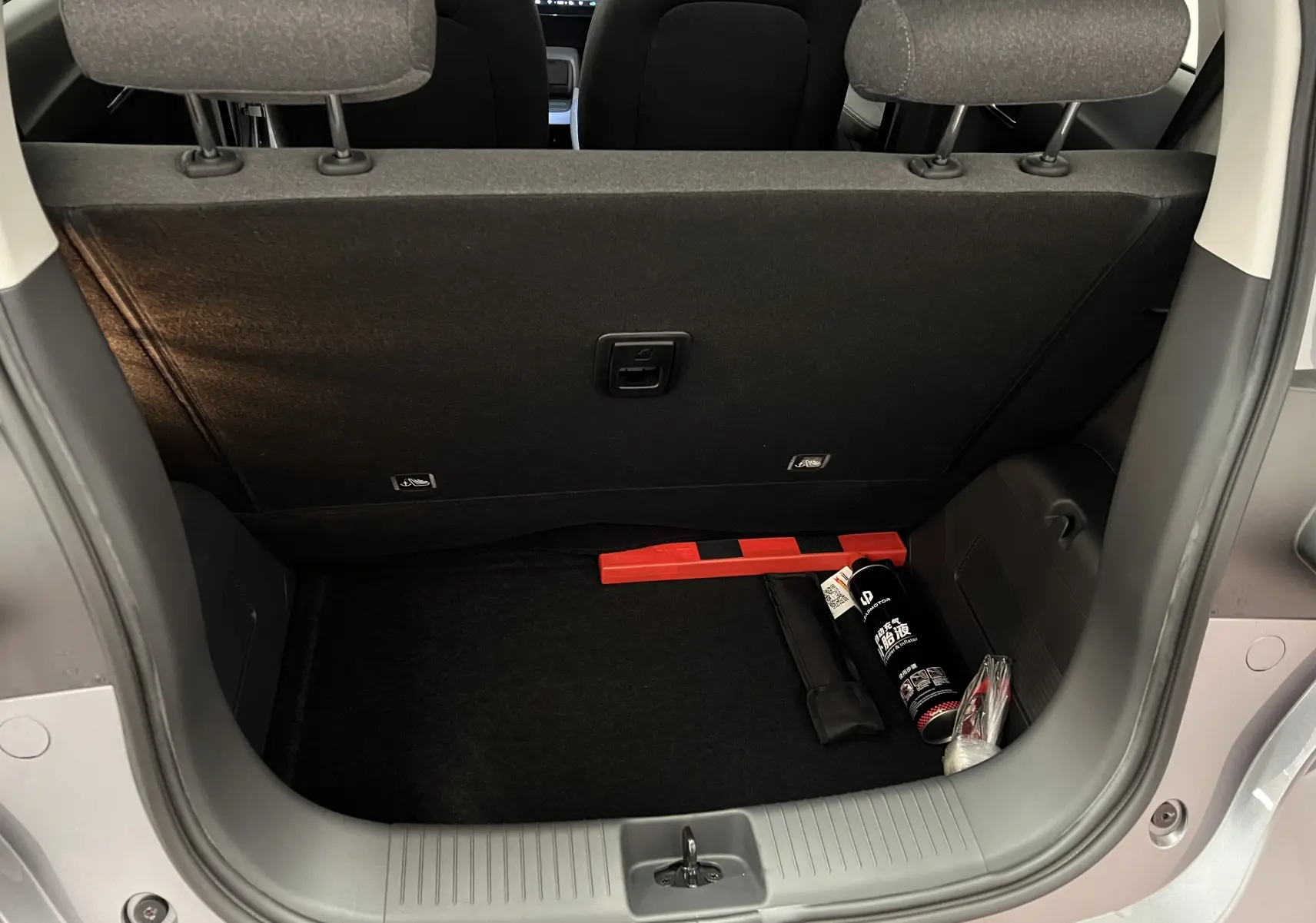 Coffre ouvert d'une Renault ZOE blanche 2024, vue arrière montrant un espace de rangement avec accessoires de sécurité.