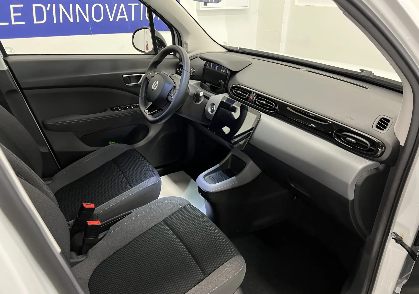 Intérieur côté conducteur de la Renault ZOE blanche 2024, montrant tableau de bord moderne et sièges tissu noir et gris.
