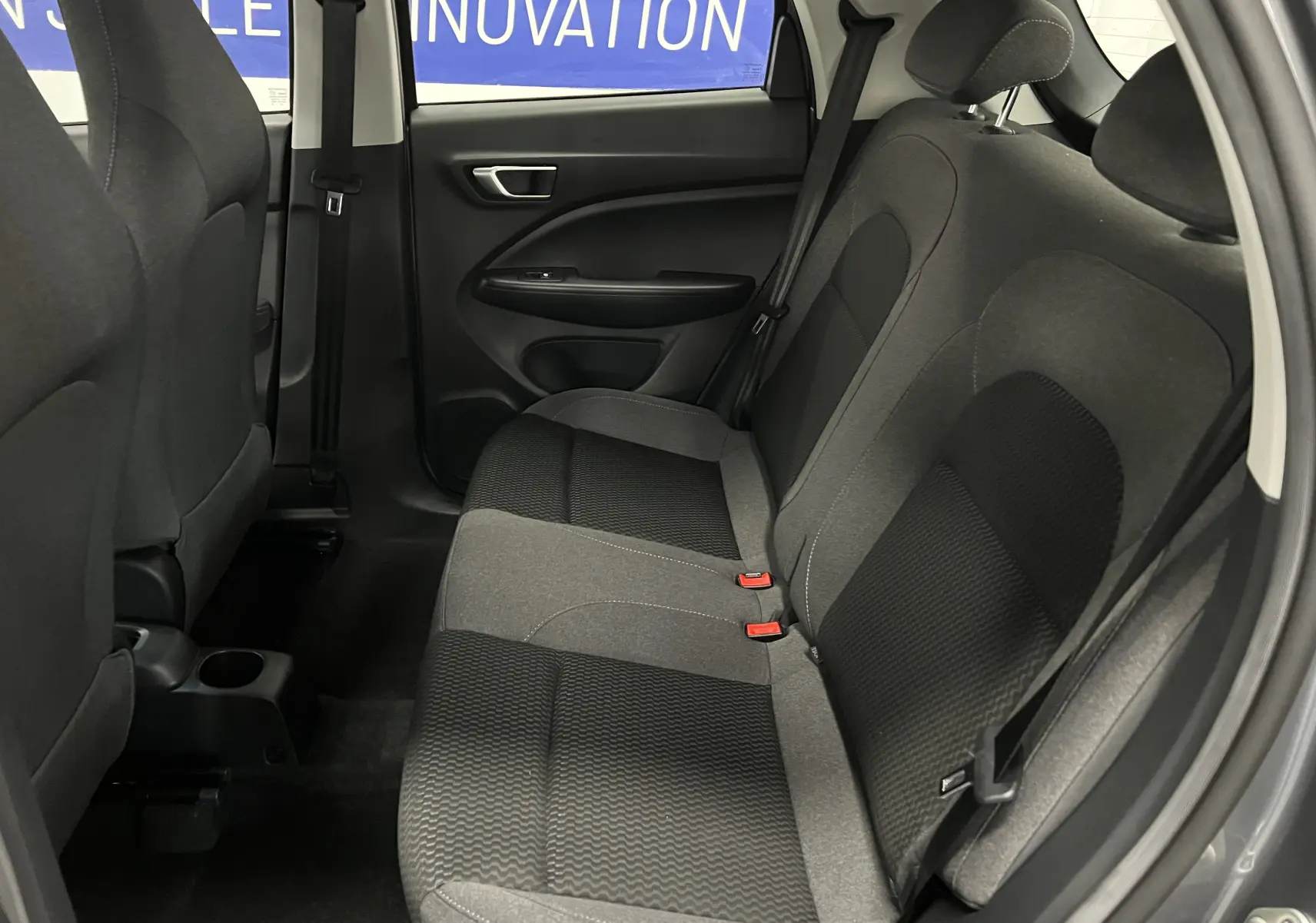 Vue intérieure côté droit des sièges arrière en tissu gris et noir de la Renault ZOE blanche 2024 électrique.