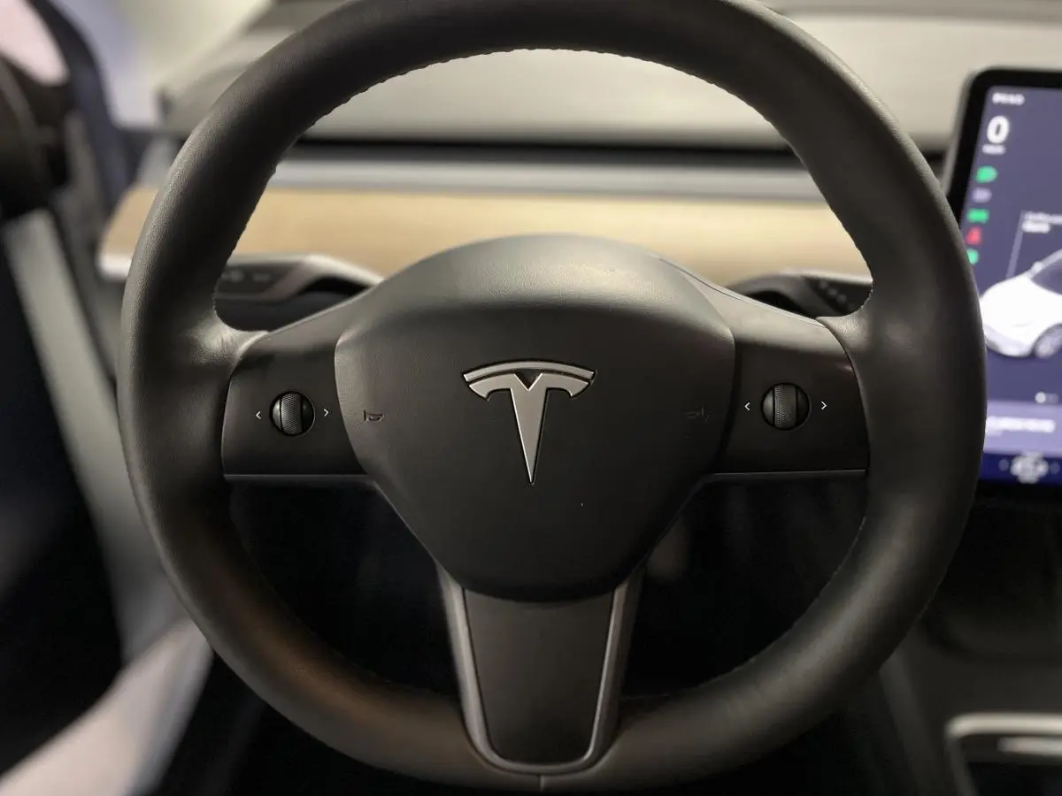Volant noir Tesla Model Y 2022 en gros plan avec logo central et écran tactile partiel visible à droite