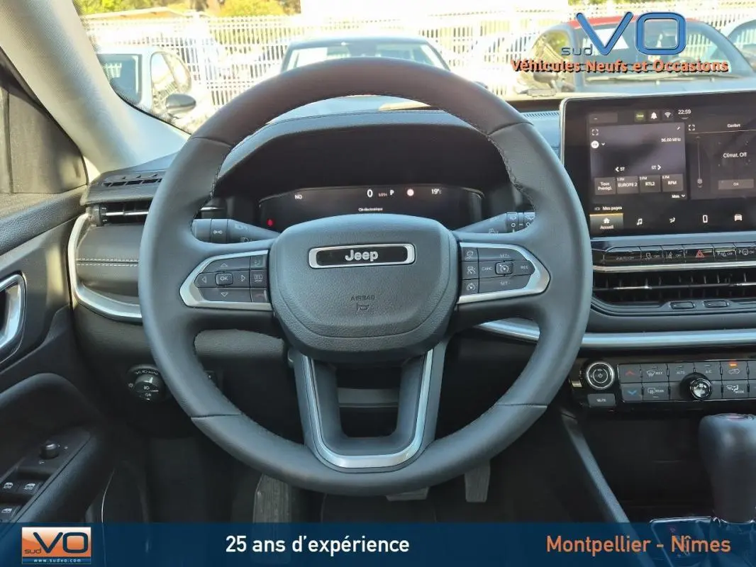 Vue centrée sur le volant Jeep noir et le tableau de bord moderne du Compass 2024 avec écran tactile allumé.