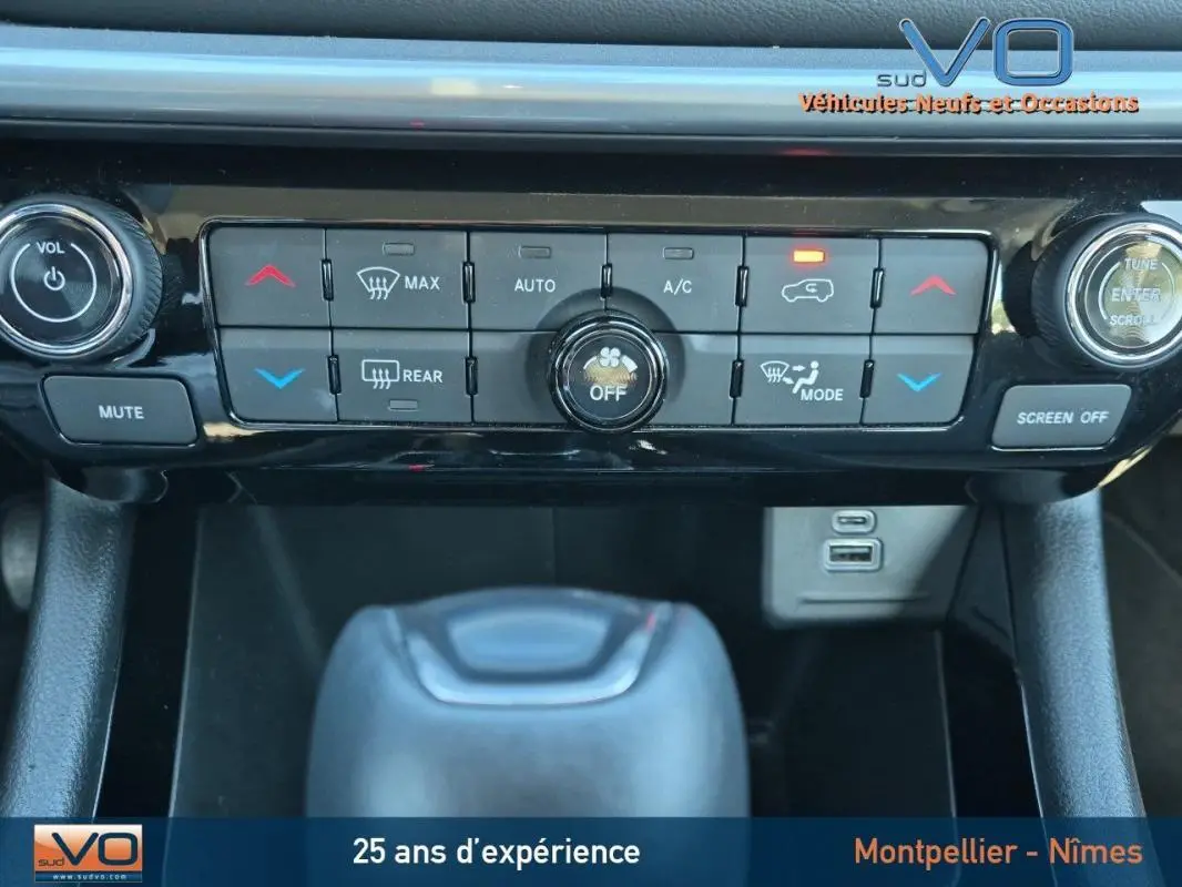 Gros plan sur la console centrale du Jeep Compass gris 2024, montrant commandes climatisation et prises USB.