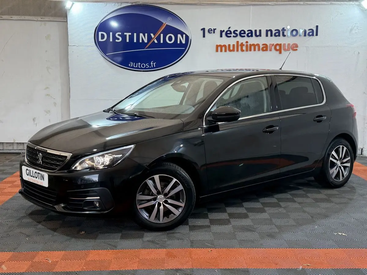 Peugeot 308 Puretech noir vue de 3/4 avant droit, avec phares allumés et jantes alliage distinctives.