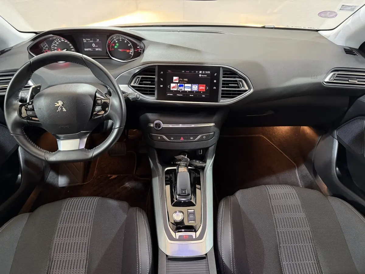 Intérieur noir de la Peugeot 308 Puretech 130, vue frontale du tableau de bord avec écran tactile et volant cuir.