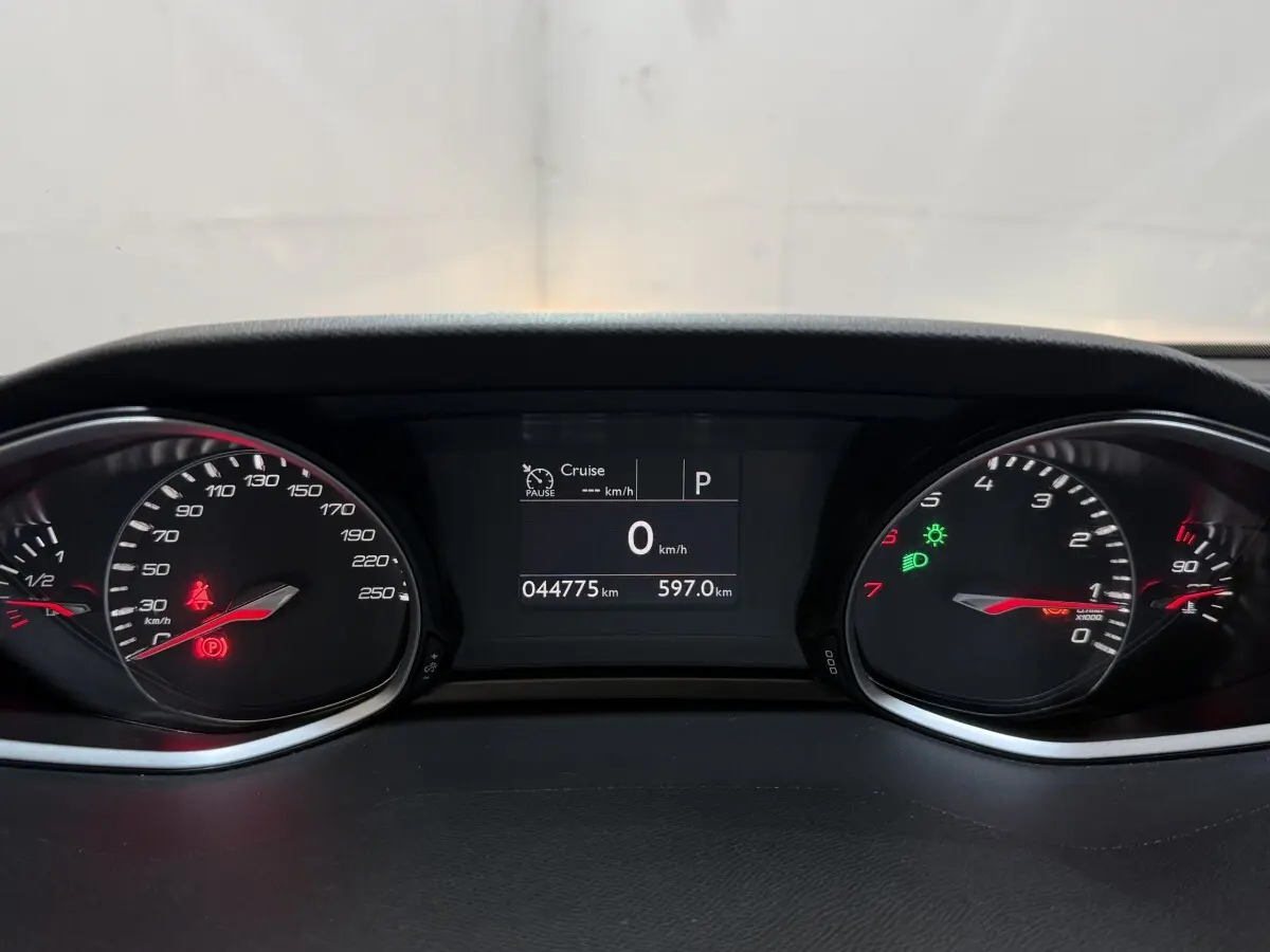 Tableau de bord de Peugeot 308 noir, affichage digital au centre avec compteurs analogiques et témoins lumineux allumés.