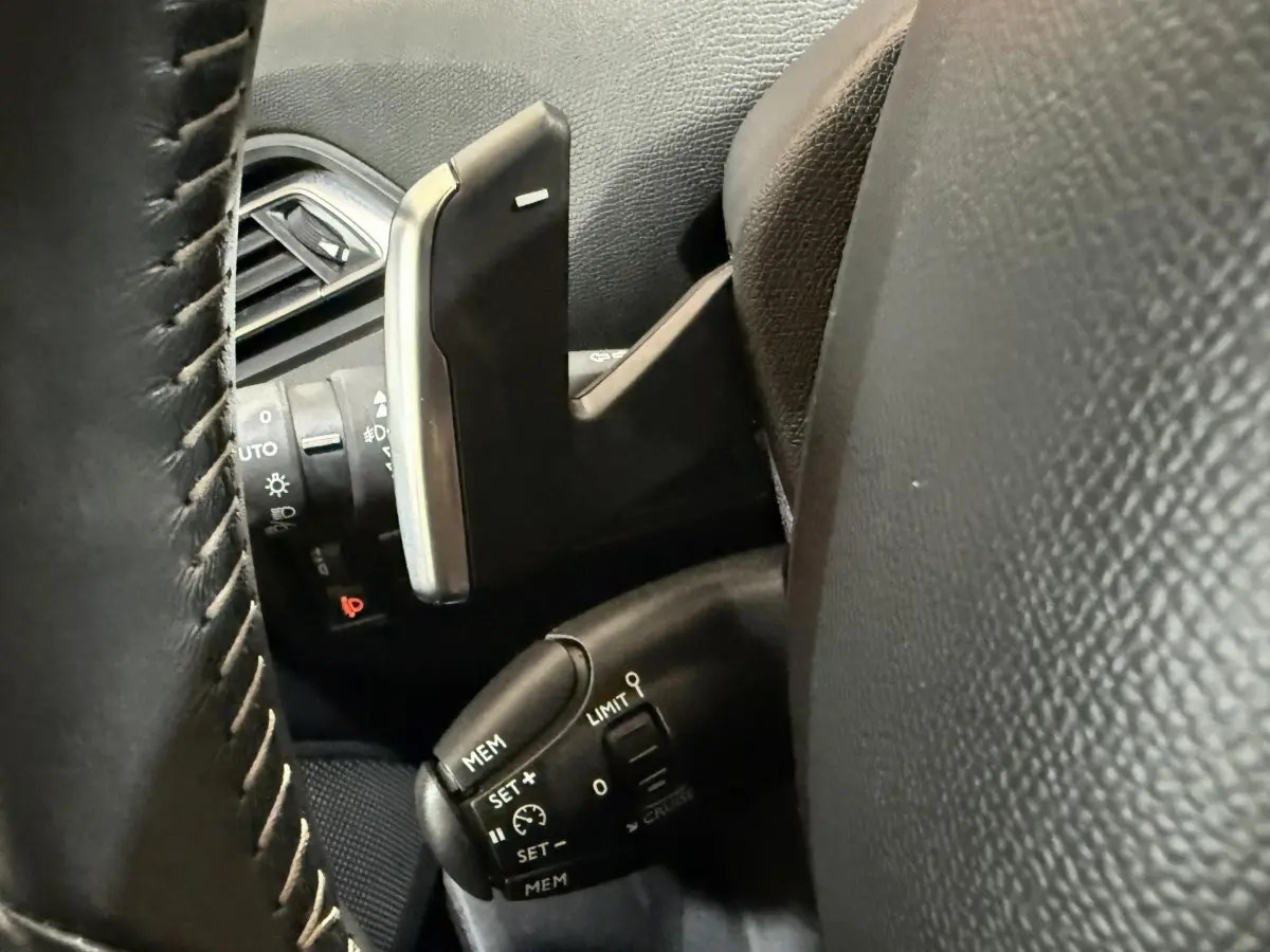 Gros plan sur les commandes de régulateur de vitesse et palettes au volant cuir noir de la Peugeot 308 2020.