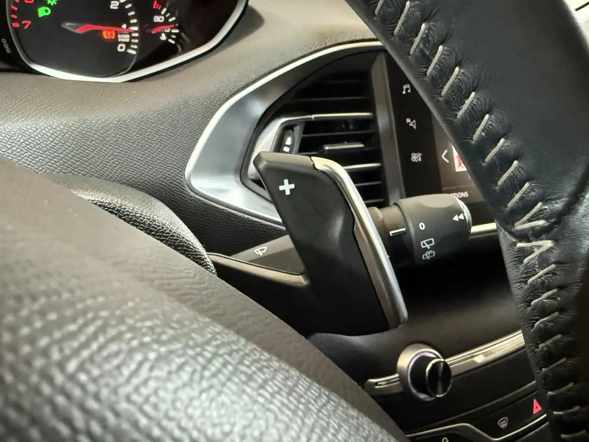 Gros plan sur la palette de changement de vitesse côté gauche du volant cuir noir d'une Peugeot 308 Puretech 130 Allure 2020.