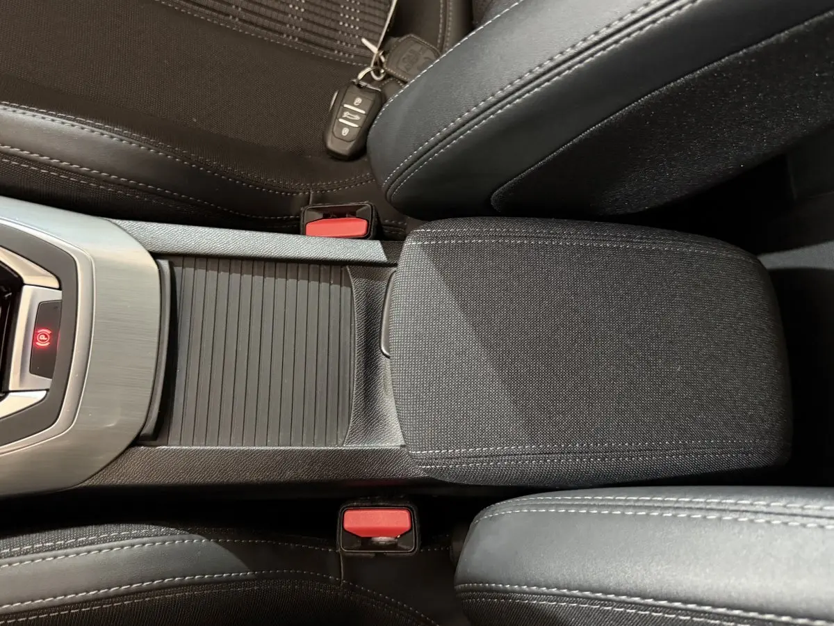 Vue rapprochée de la console centrale noire et des sièges tissu et cuir d'une Peugeot 308 Puretech 130 Allure 2020.