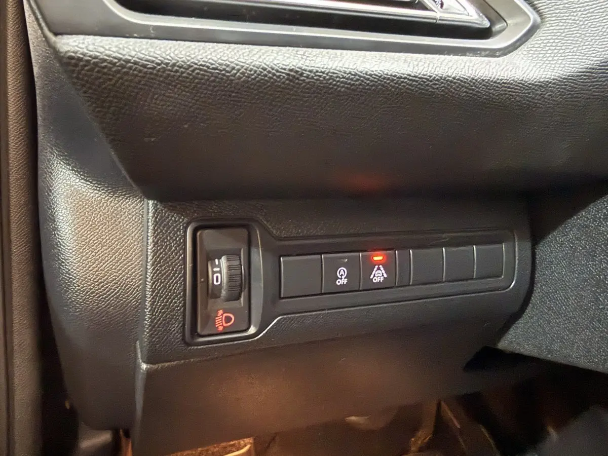 Gros plan sur les commandes d'éclairage et d'assistance au freinage côté gauche du tableau de bord d'une Peugeot 308 noire.