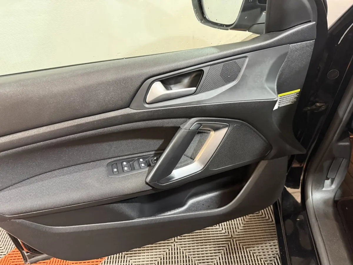 Vue rapprochée de la porte avant gauche noire du Peugeot 308 2020, avec commandes de vitres et poignée argentée.
