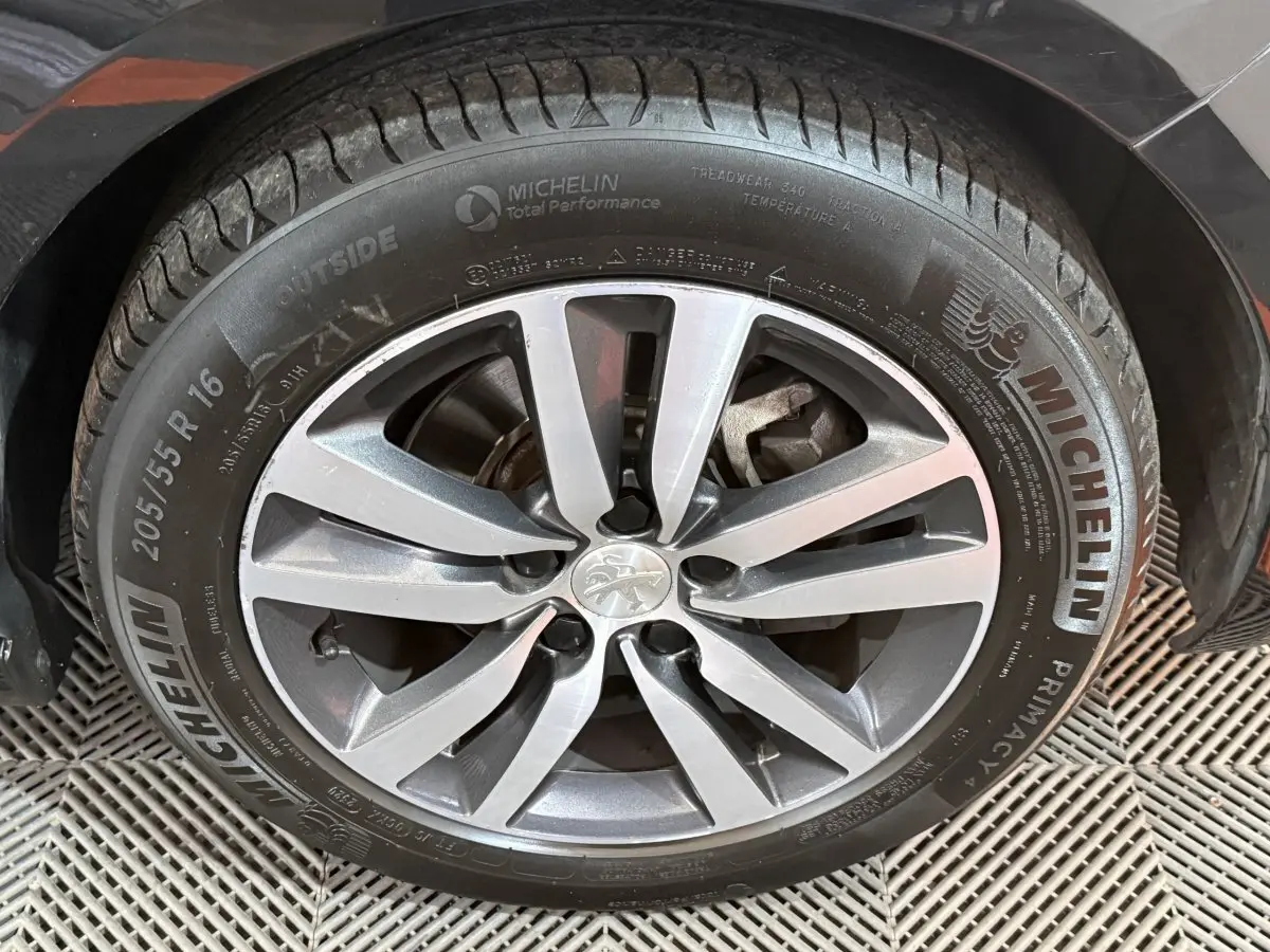 Gros plan sur la roue avant gauche d'une Peugeot 308 noire avec jante alliage et pneu Michelin.