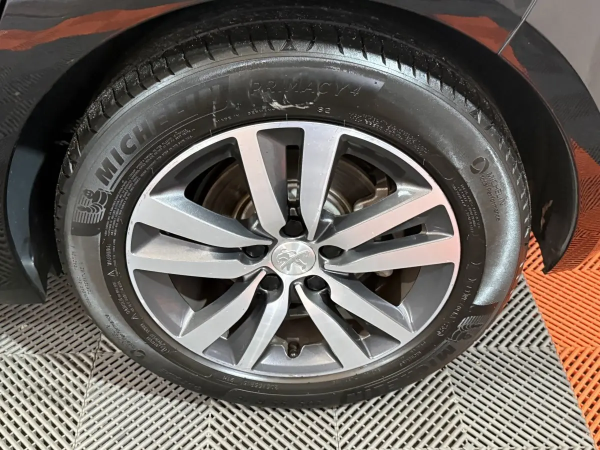Gros plan sur la roue avant droite d'une Peugeot 308 noire avec jante alliage et pneu Michelin Primacy 4.