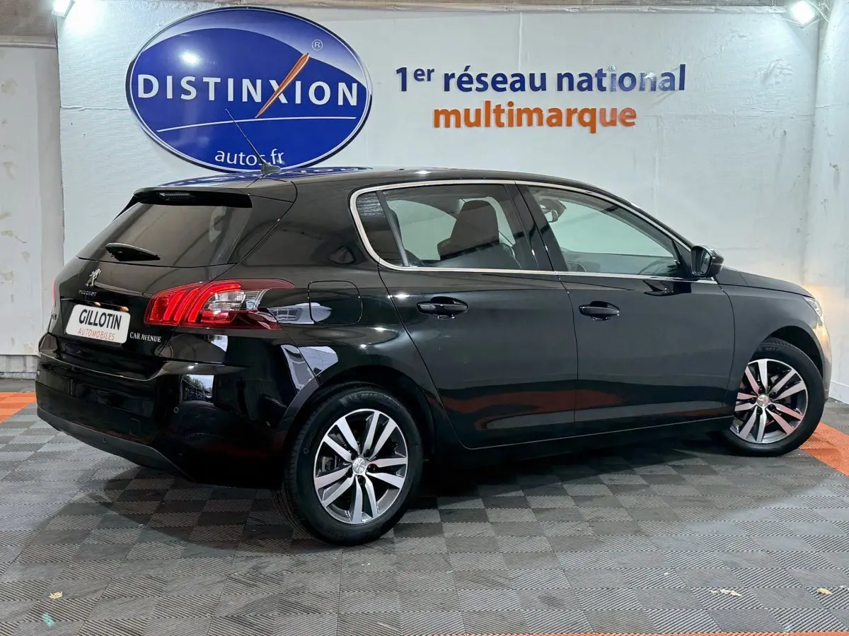 Peugeot 308 noire vue de profil côté droit dans un showroom avec logo Distinxion en arrière-plan.
