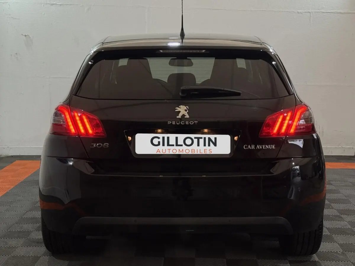 Vue arrière d'une Peugeot 308 noire de 2020 avec feux arrière allumés dans un garage fermé.