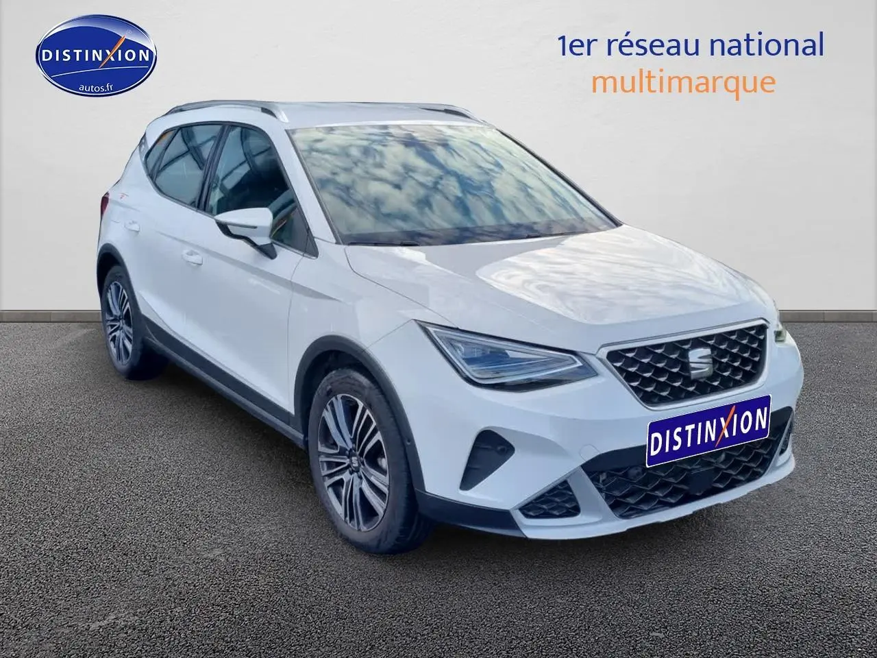 SEAT Arona blanc en 3/4 avant droit, avec jantes alu 17 pouces et barres de toit visibles.