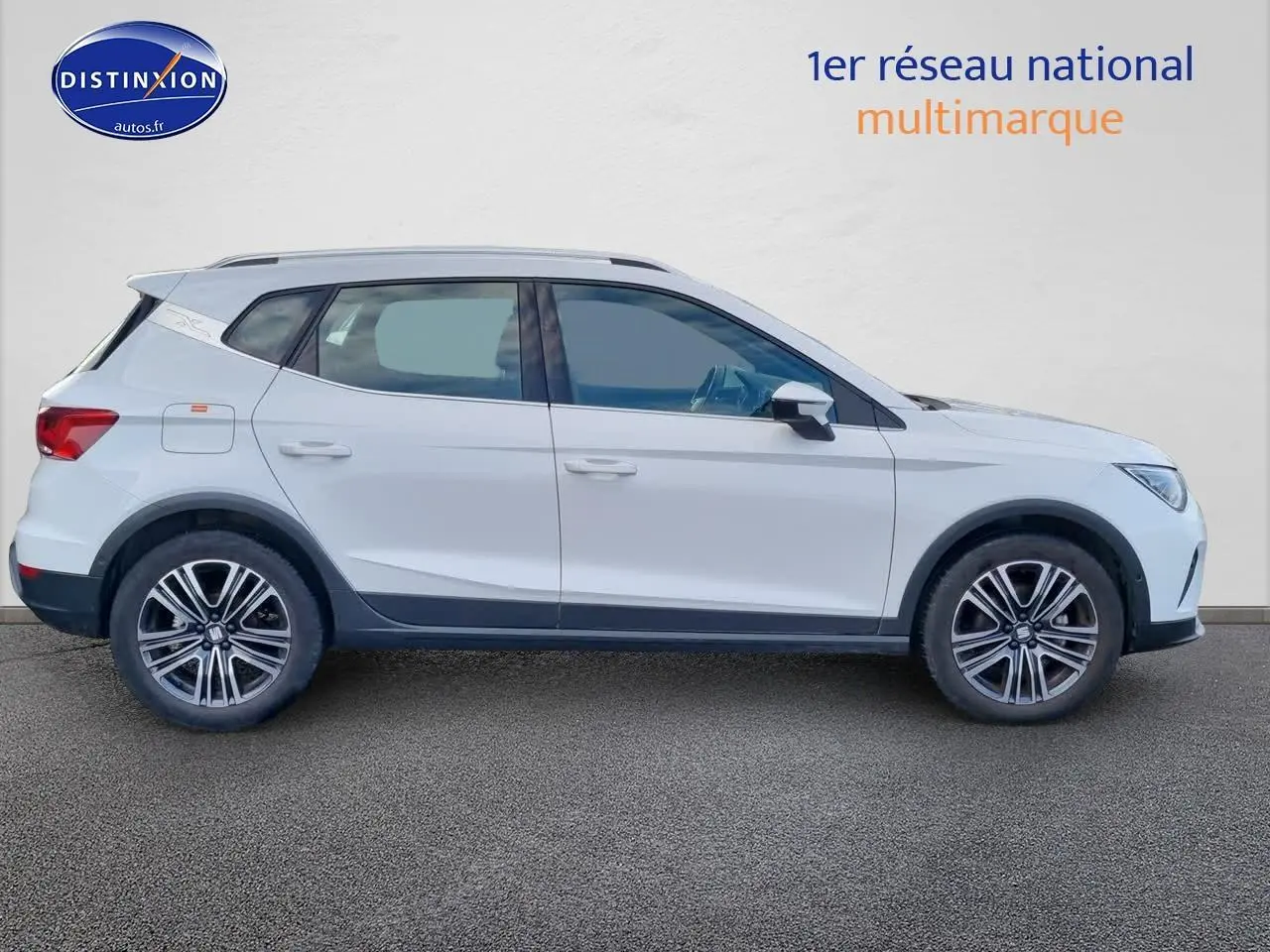 Vue de profil côté gauche d'un SEAT Arona blanc 2023 avec jantes alliage et barres de toit noires.