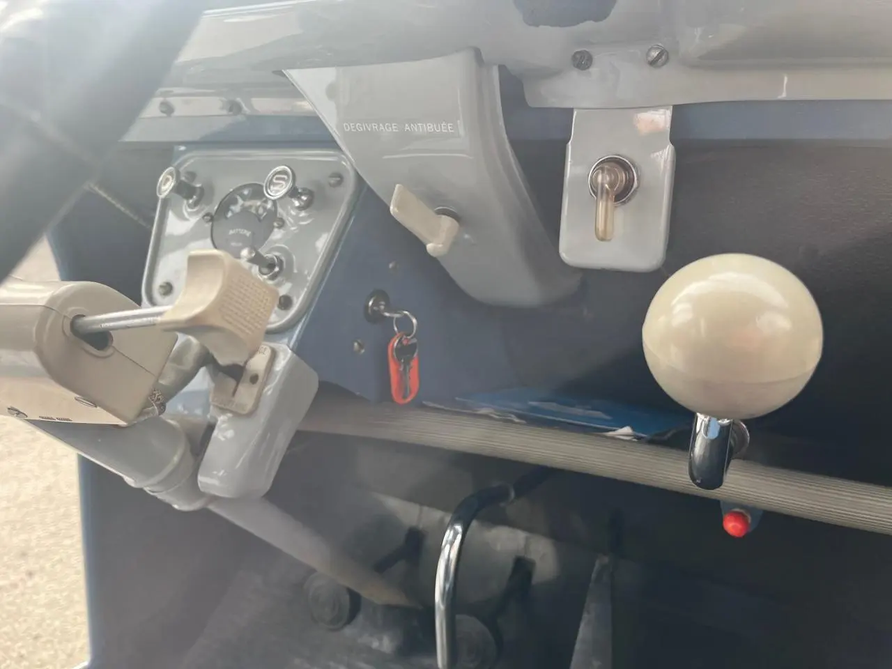 Vue rapprochée de l’intérieur bleu clair d’une Citroën 2 CV 1960, montrant le tableau de bord et levier de vitesses blanc.