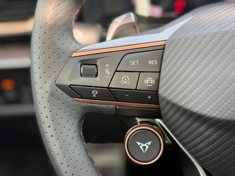 Gros plan sur la partie gauche du volant perforé gris du CUPRA Formentor 2026 avec commandes multifonctions et insert cuivre.