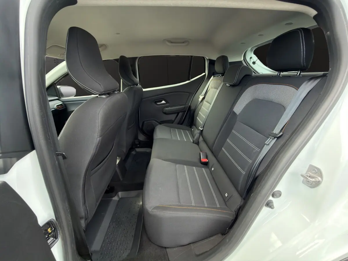 Vue intérieure arrière de la Dacia Sandero Stepway blanche, montrant la banquette noire avec surpiqûres contrastantes.