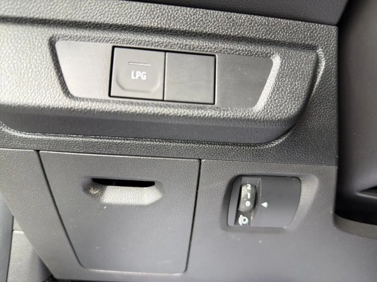Gros plan sur le tableau de bord côté conducteur de la Dacia Sandero Stepway blanc, bouton LPG et réglage phare visible.