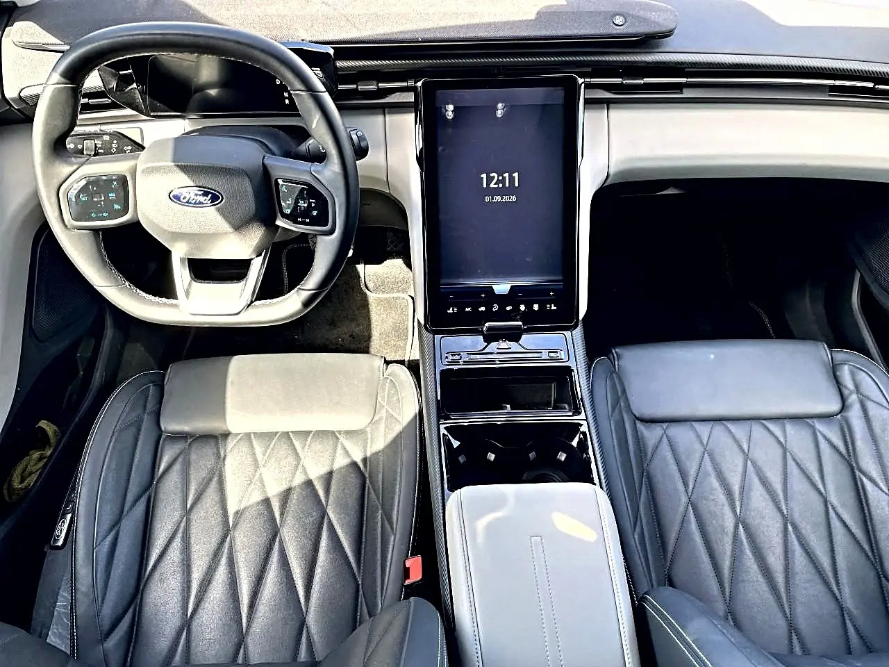 Vue intérieure de face du Ford Explorer 2025 gris, montrant le volant multifonction et l'écran tactile central vertical.
