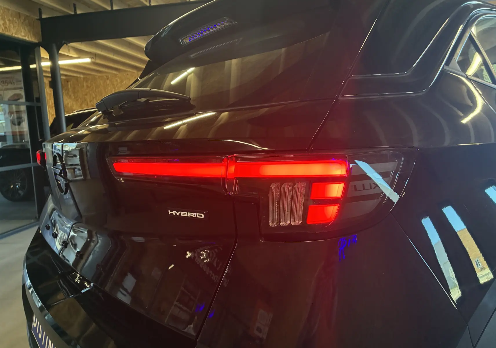 Vue arrière droite d'un Opel Mokka noir 2025 avec feux LED allumés et badge Hybrid visible sur le hayon.