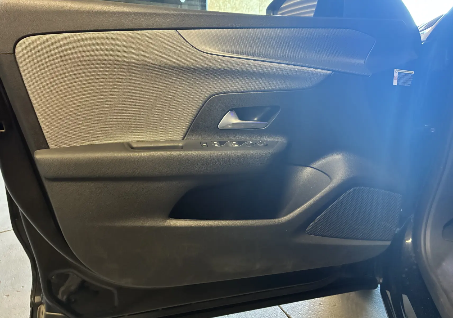 Intérieur de la porte côté gauche de l’Opel Mokka 2025 noir, avec commandes de vitres et haut-parleur intégré.