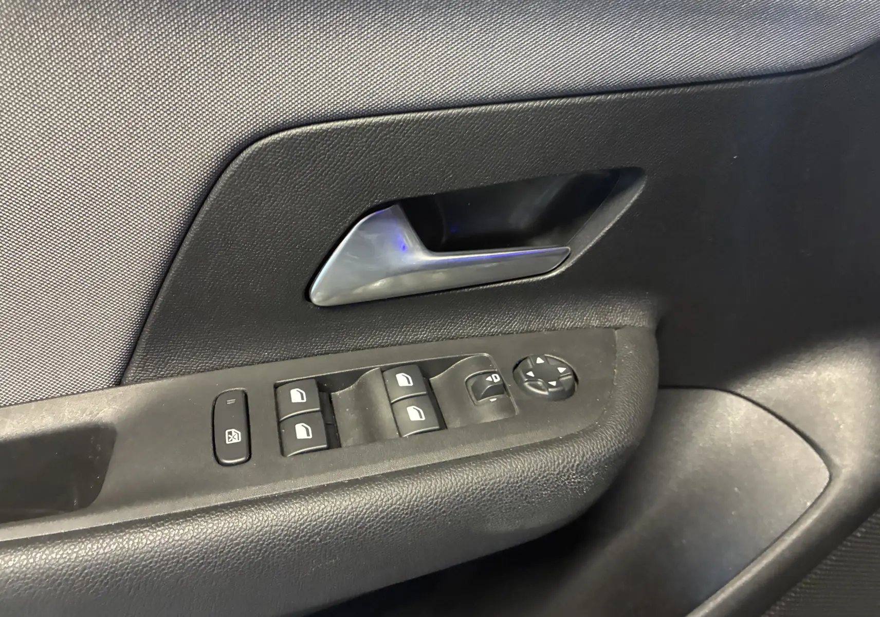 Gros plan sur la poignée intérieure et les commandes de lève-vitres côté conducteur de l’Opel Mokka noir 2025.