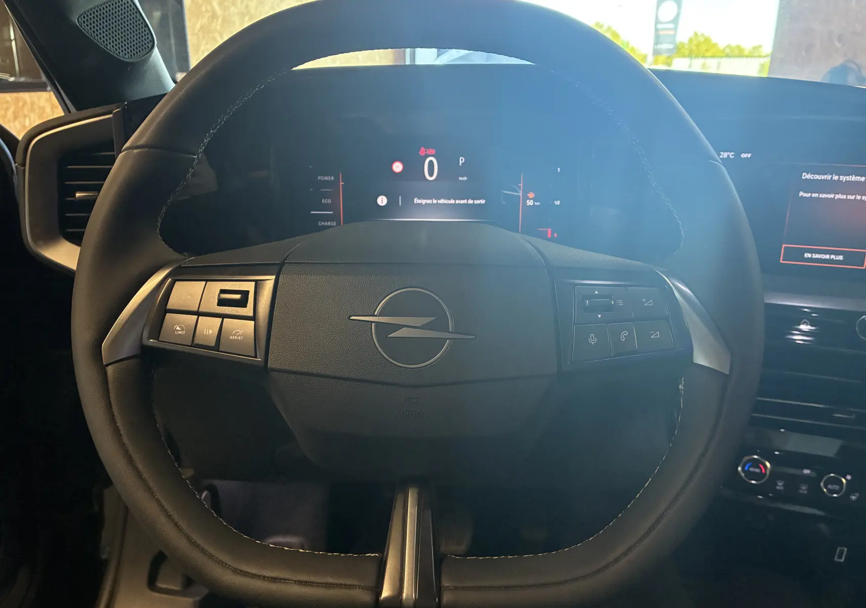 Vue rapprochée du volant noir de l’Opel Mokka 2025, avec commandes intégrées et tableau de bord numérique allumé.