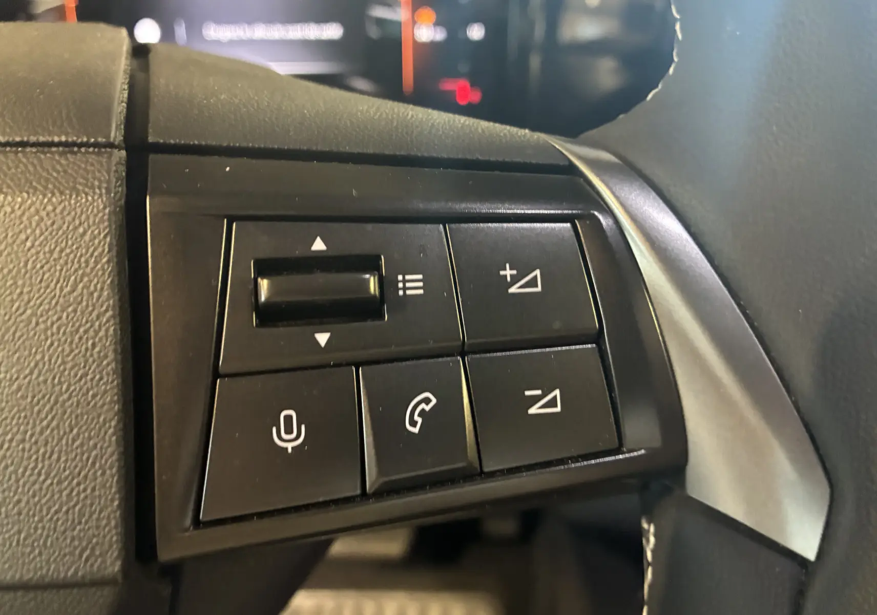 Gros plan sur les commandes de volume et téléphone au volant du Opel Mokka noir 2025, version hybride.